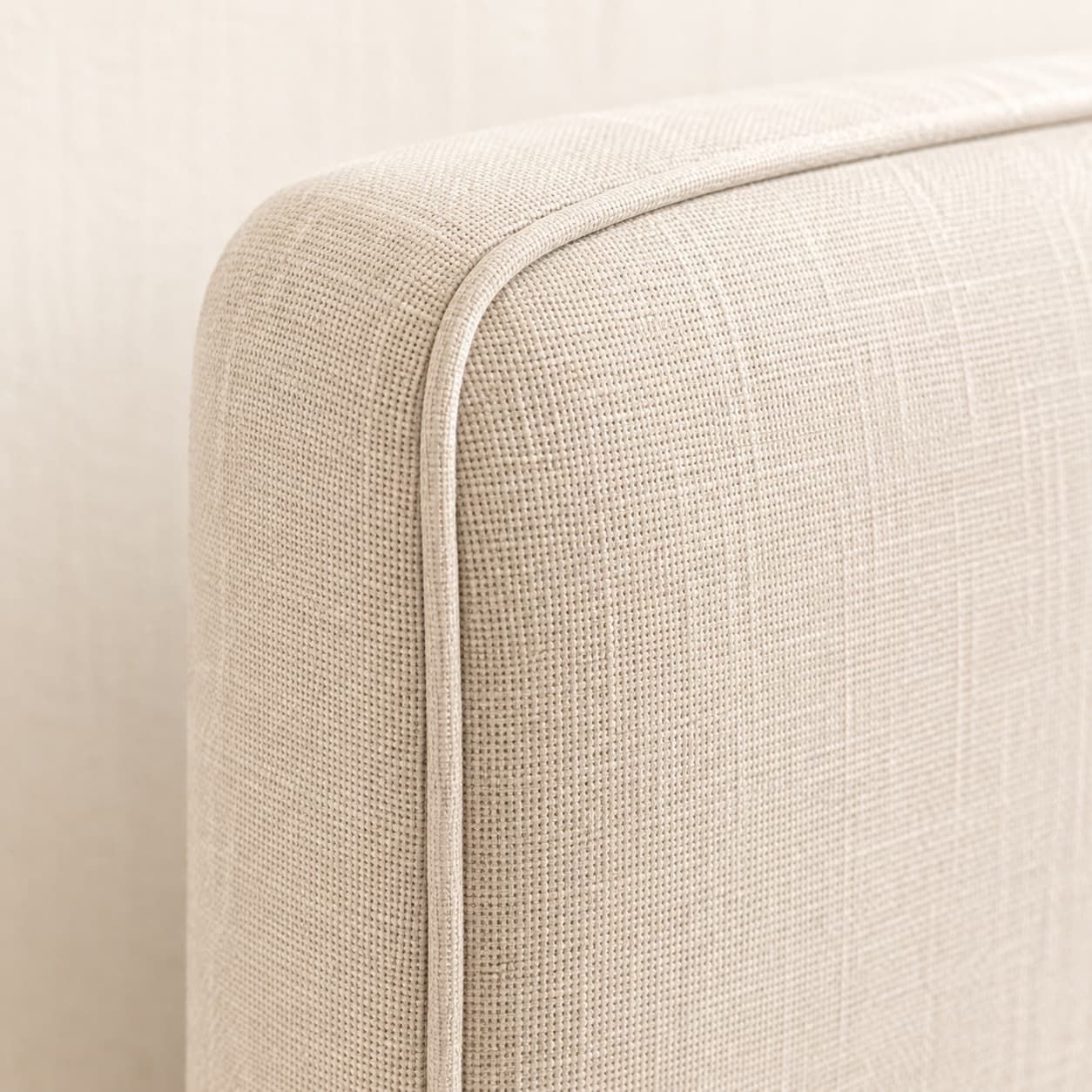 Piped edge on a linen-upholstered headboard