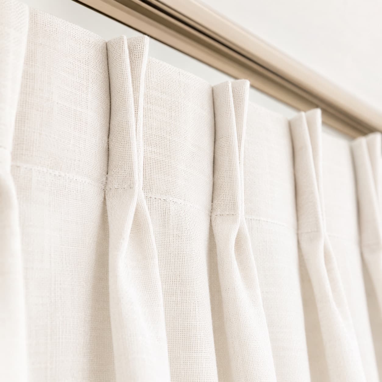 Pinch-pleat heading on a white linen curtain